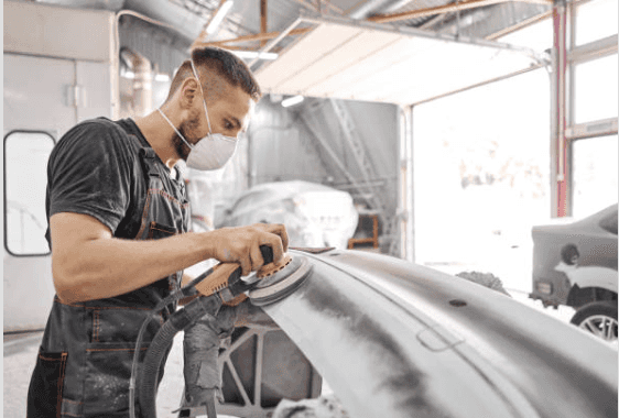 A technician sanding a repaired body panel