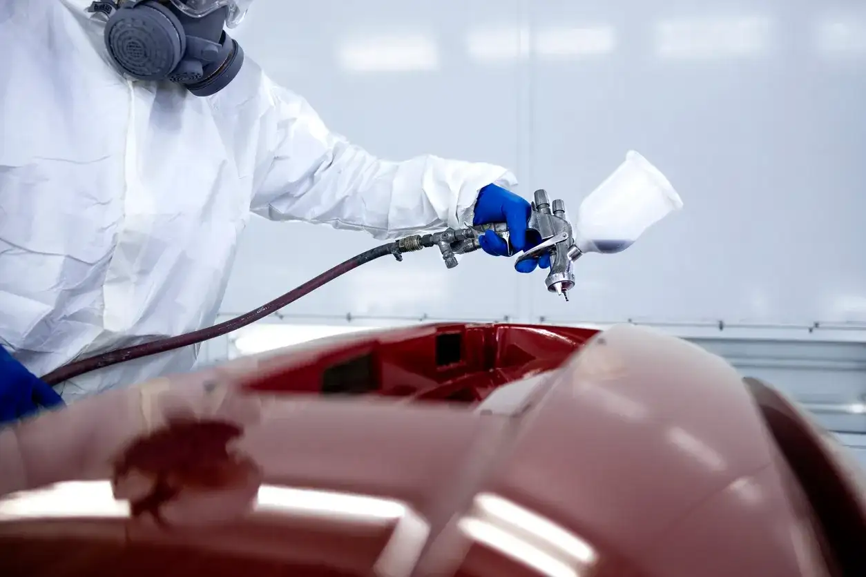 A technician applying a factory-match finish in the paint booth